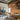 Two Ilo horizontal pendants over a long dining table in a loft with wood shelving and beams