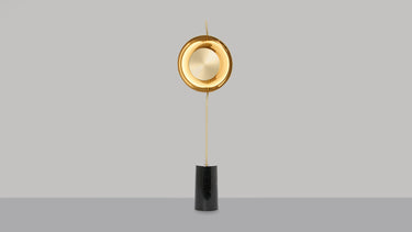 Pendulum floor lamp in satin brass with a smoked glass shade on a black marble base, studio view