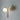 Big Bulb wall light in polished brass lit on a dark grey wall, with the shadow of its arm behind it