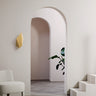 Abstract wall light, a brass leaf shape, on a pale wall beside an arched doorway