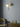 Big Bulb wall light in polished brass with a lit opal globe on a blue-grey wall above a green armchair and a brass table