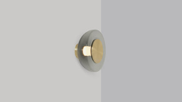 Pendulum wall light in satin brass with a smoked glass shade, studio view
