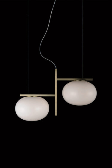 Oluce Alba 468 pendant light in satin brass with two blown glass spheres on a dark studio background