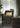 Oluce Plume table lamp on a side table next to a velvet armchair