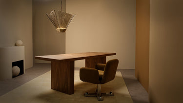 Shard pendant with bronze kiln glass panels above a wooden desk and a brown swivel chair