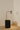 Heron table lamp with a slim stem and a cylindrical shade, in a room setting