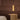 Ring pendant in satin brass hanging beside a bed against a walnut-paneled wall