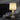 Acropolis alabaster table lamp glowing on a side table beside a boucle armchair in a dark room