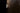 Cielo wall light in satin brass seen from the side against a dark textured wall