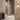 Gaia wall lights in bronze with matt opal glass on a plaster wall beside a stair and a dark console, shown with the short version