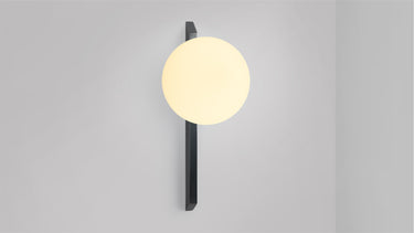 Tall Gaia wall light in bronze with a lit matt opal glass globe, shade facing up