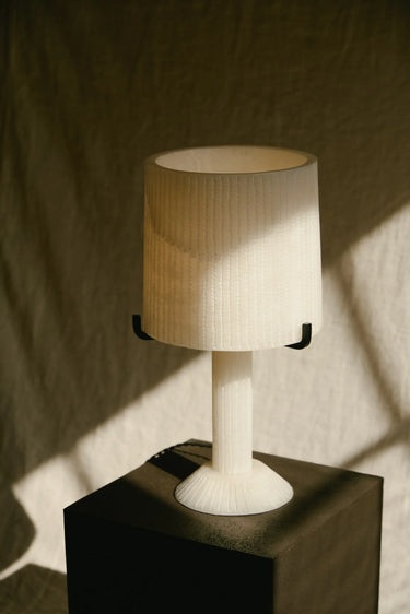 Acropolis alabaster table lamp on a black plinth in streaming window light