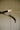 Close view of a curved bronze strand ending in a liquid cast glass shade on the Trace Linear X chandelier