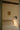 Heron wall light with a cylindrical shade on a short arm, in a room setting