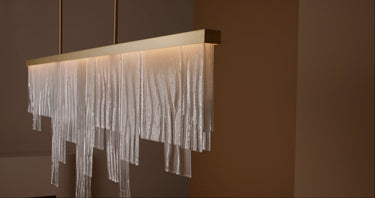 Close-up of the Cascata Long chandelier with a brass bar and hanging clear glass strips