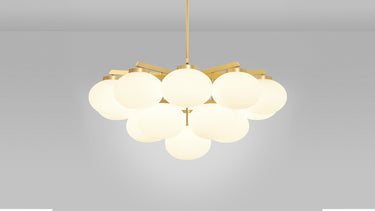Cloudesley chandelier in satin brass, lit, with tiers of matt opal glass globes