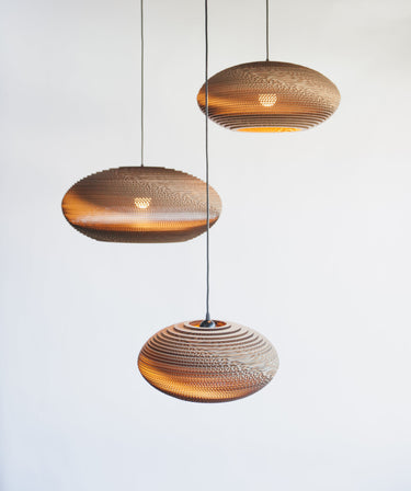 Three Natural Disc pendants hung at staggered heights against a pale wall, Graypants Scraplights