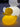 The compact size of the small Duck Yellow and White Duck Lamp by Goodnight Light shown next to a book on a nightstand for scale.