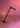 Satin black nickel Oluce Calamaio desk lamp with its LED lit, photographed against a pink backdrop