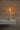 Graypants Wick GP204 portable LED lamp, brass finish, on a modern wooden nightstand.