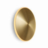 Graypants Chrona round modern brass wall sconce lit showing warm 2700K ambient glow.