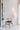 Two white Nest pendants hanging together beside a wooden chair and shelving