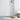ET2 Nucleus clear glass orb pendant cluster with brass spheres hanging in a bright room beside a rattan stool