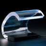 Oluce Acrilica table lamp, a curved clear acrylic lamp on a black base, studio view