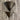 Close view of the two bronze cones of the Oluce Pascal floor lamp against a travertine wall