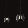 Two Oluce The Globe pendants in satin nickel, small and large, on a dark studio background