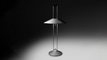 Regina T lamp lit in a dark room, casting a pool of indirect light on the surface below