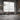 ET2 Rollo tube pendant hung in an industrial loft with a brick wall, tall windows and a small bistro table