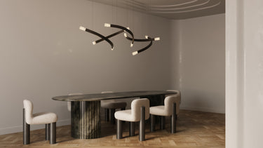 Trace Linear chandelier with crossing bronze strands and glass tips above a long dark oval dining table with cream chairs