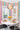 ET2 Sense mirror chrome flush mount in a bright breakfast nook with colorful geometric wallpaper and bay windows