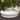 White round Sun Pad daybed on a wooden deck with dark pillows and a woven throw