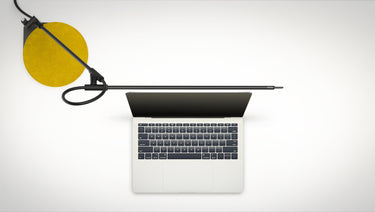 Black Superlight by Pablo over a laptop workspace with a mustard felt pad