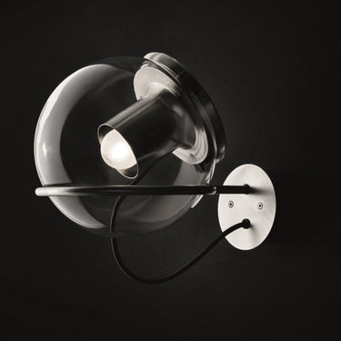 Oluce The Globe wall lamp in satin nickel with transparent glass sphere on a dark studio background