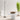 Moneta Medium floor lamp in Black beside a round white pedestal table with a bowl, tall grasses behind