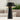 Black Sesa Short Accent table lamp lit on a patio table in front of an outdoor sofa