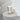 Close view of the Caspe 8 lamp lit on a white side table, with a cream sphere beside it