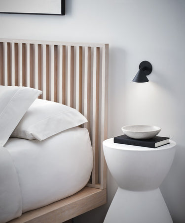 Midrand 4 Task Sconce by Sean Lavin in Nightshade Black, mounted beside a bed and lit