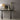 Braque table lamp on a dark console beside a framed round artwork and a glass vase