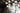 Cluster of white Graypants Scraplights cardboard pendants hanging at varied heights in a tall loft space