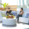 White round Puck ottoman used as a coffee table with a fruit tray in front of a curved white cabana sectional