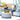 White round Puck ottoman used as a coffee table with a fruit tray in front of a curved white cabana sectional