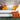 Crib daybed with two Lean wedge headboards, orange and patterned pillows and candles against a dark stone wall