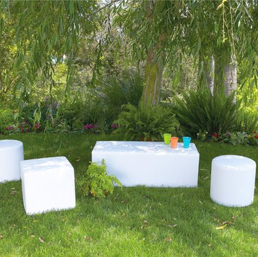 White Dash bench with Dot cylinder and cube ottomans on a lawn with colorful cups