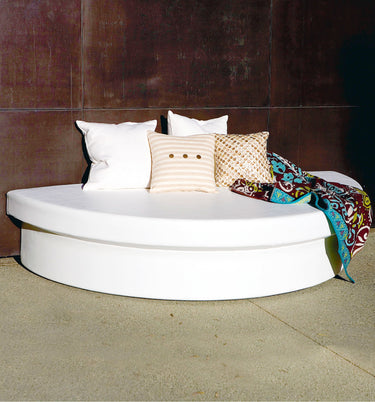 White semi-circle Moon Pad daybed against a dark wall with white and striped pillows and a patterned throw