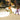 Children playing on white oval pads on sand under a pavilion