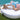 Woman lounging on a white round La Fête Sun Pad daybed with striped pillows beside a swimming pool